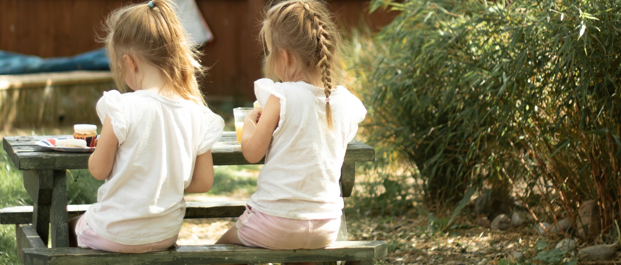 two-girls-sitting-at-a-bench-eating-together