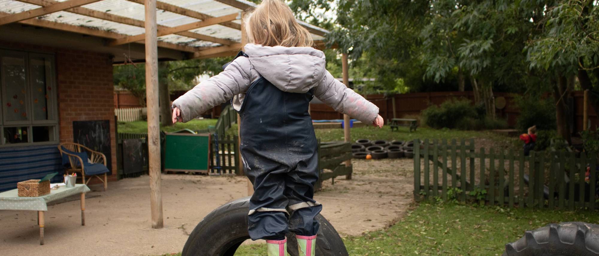 child-stands-on-tyre-arms-out-stretched
