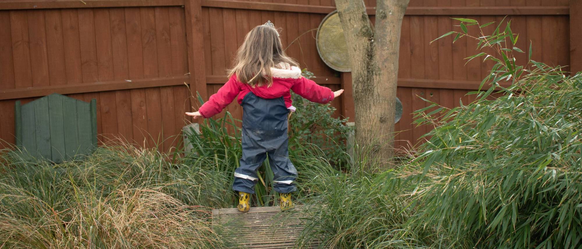 girl-standing-on-balance-beam-outside-with-her-arms-out-stretched