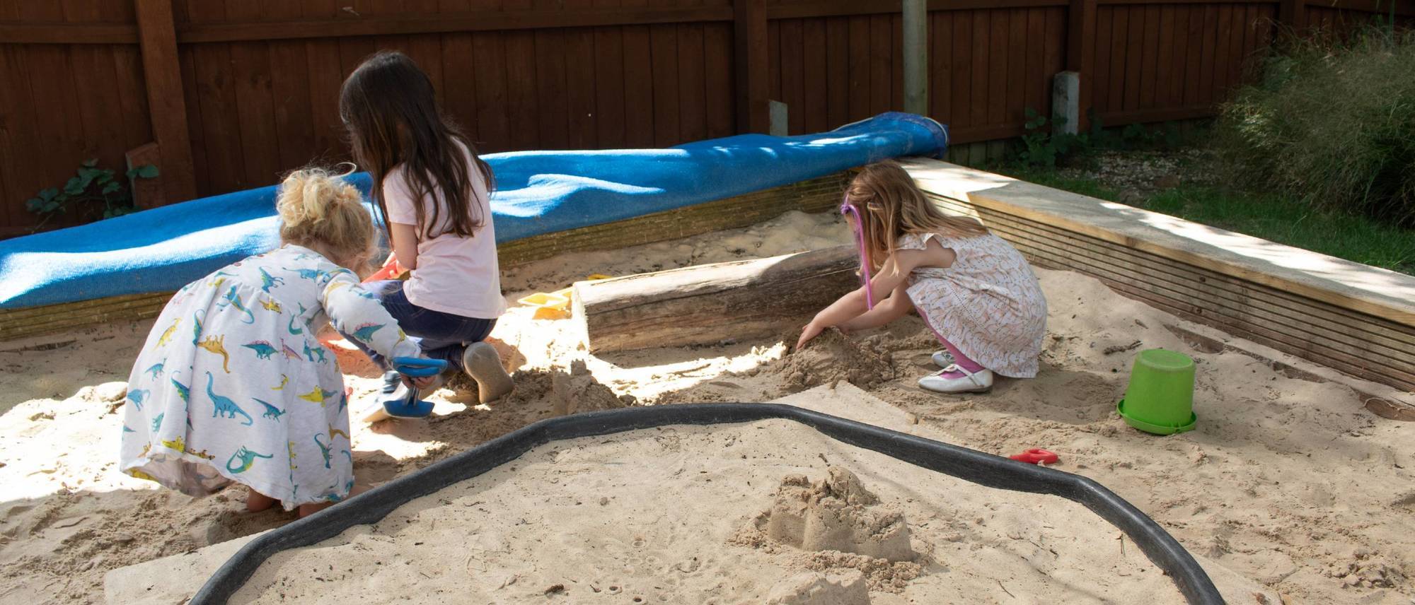 girls-playing-in-sandpit-on-sunny-day